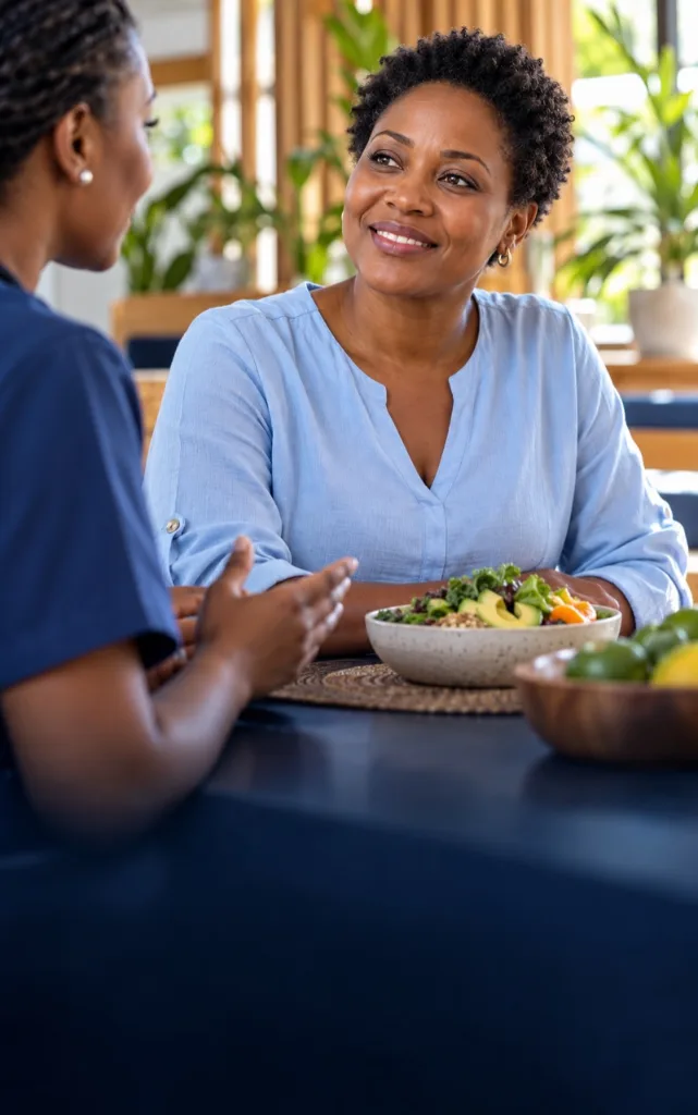 Woman smiling over a bowl of salad while talking with a clinician